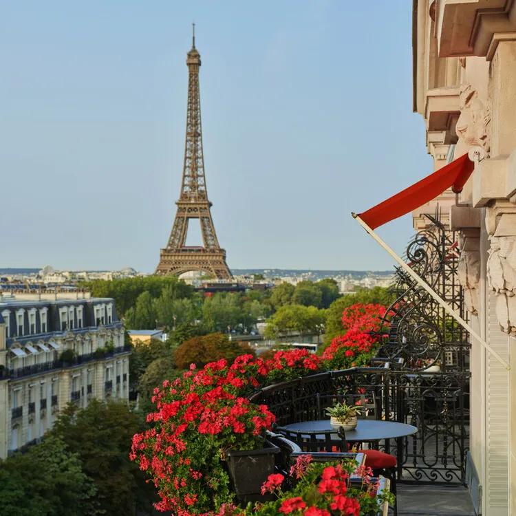 A geranium-draped Plaza Athénée balcony looking out to the Eiffel Tower